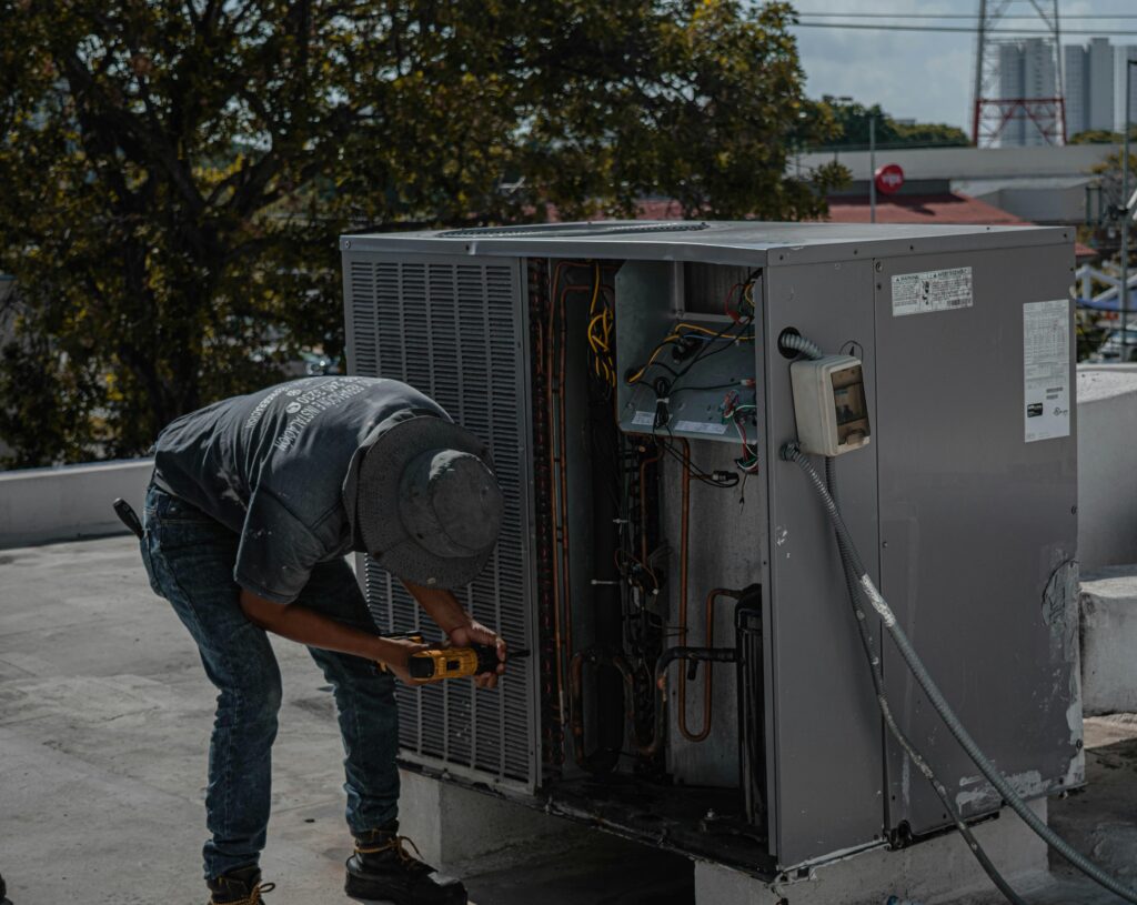 Tech AC A technician is repairing an air conditioning unit on a rooftop, demonstrating skilled manual work.