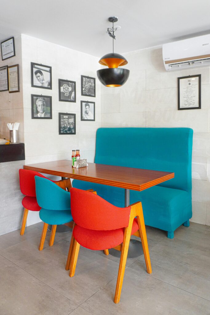 pexels-photo-27605499-27605499 Bright and inviting café seating area with colorful chairs and framed art on the walls.