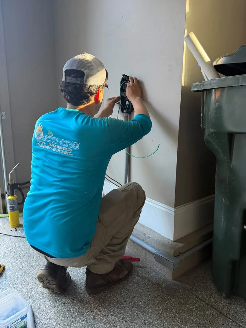Eco-One electrical technician mounting a Tesla Wall Connector and conduit in a garage