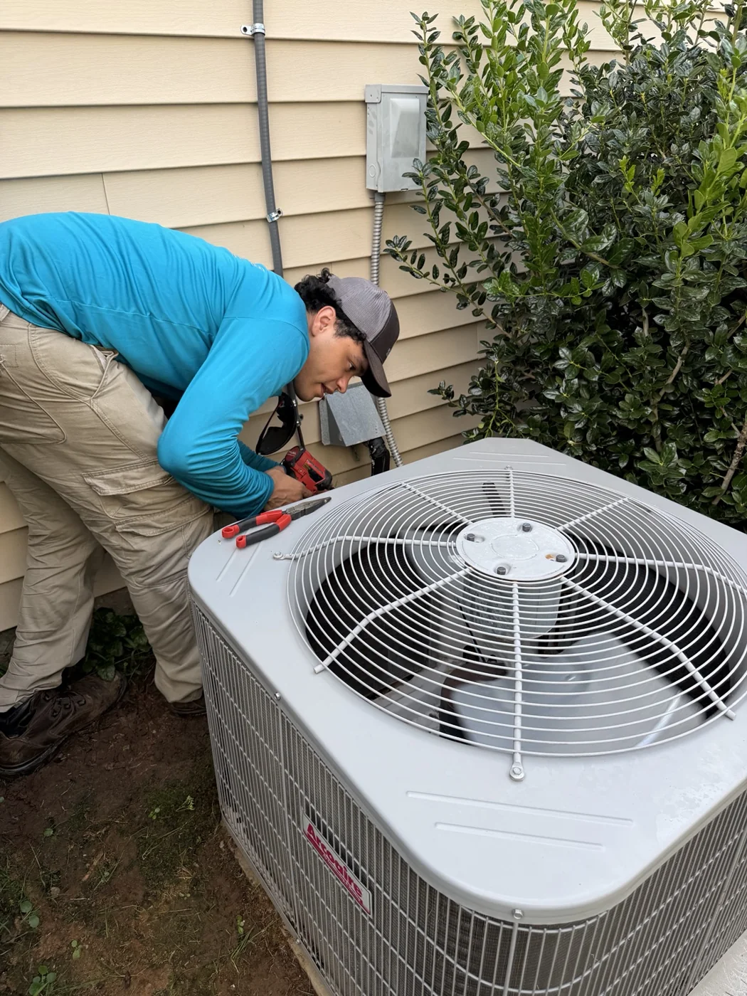 Eco-One technician inspecting an outdoor air-conditioning unit at a local home