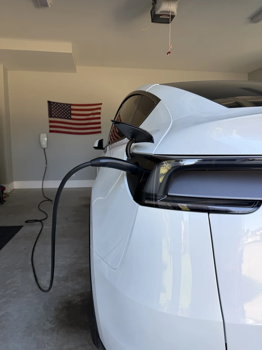 Tesla charging from a wall-mounted home charger in a residential garage